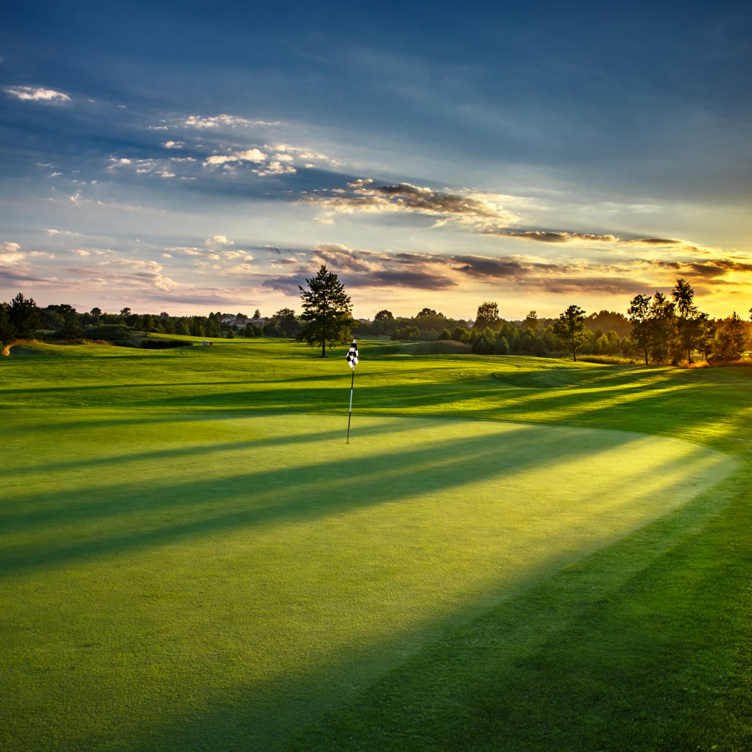 Golf course green at sunset with a flagstick and long shadows